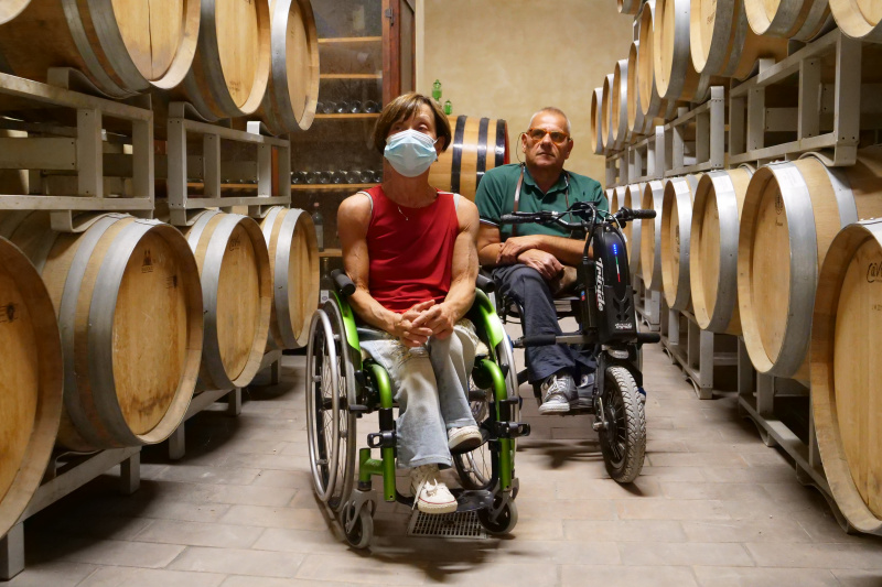 Two people in adapted wheelchairs in the cellars of the vineyard