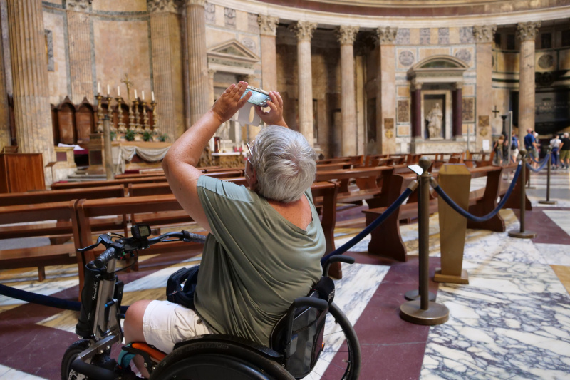 A person in a wheelchair takes a photo of the architecture of the Pantheon