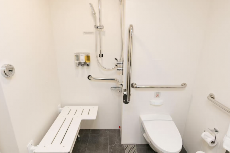 The ensuite restroom has a roll-in shower with no threshold, grabs bars, and a shower bench
