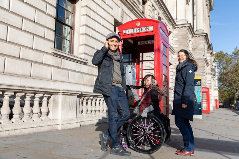 A tour group posing next to a red telephone box