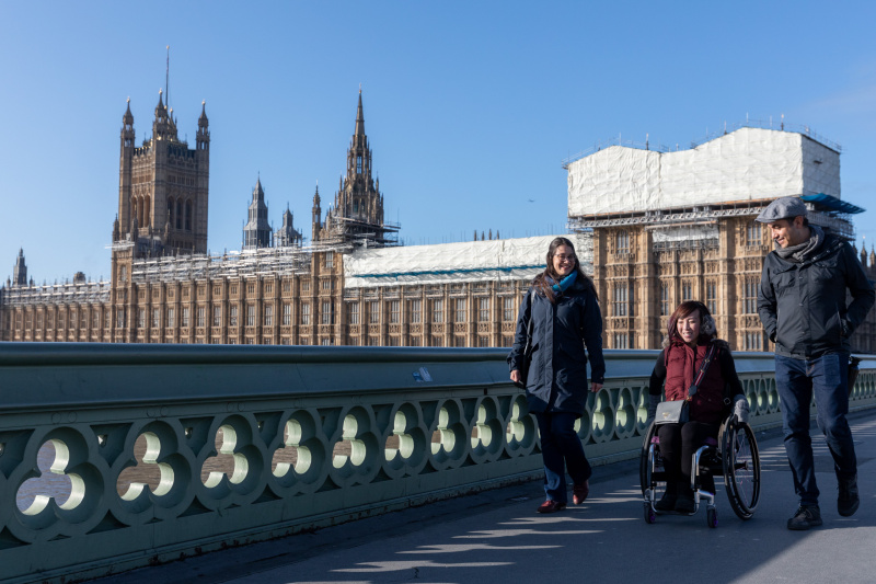 Tour participants crossing Westminster Bridge by foot and in a wheelchair.