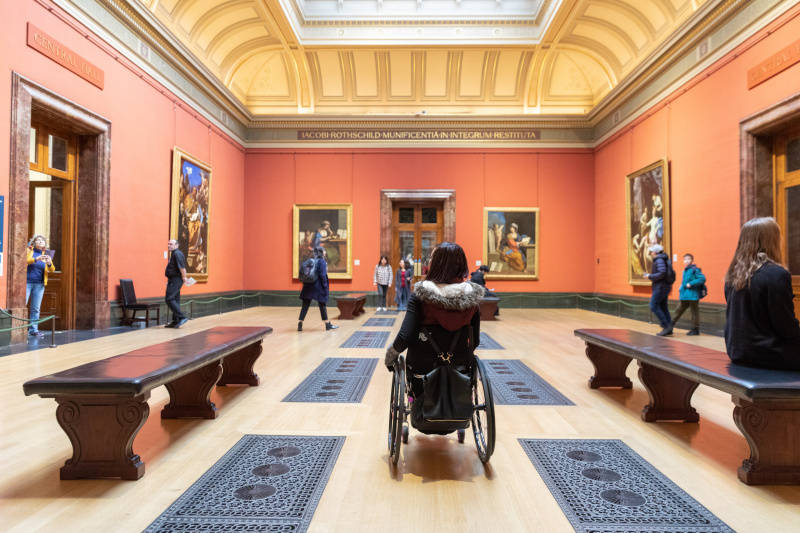 A person in a wheelchair in a large art gallery