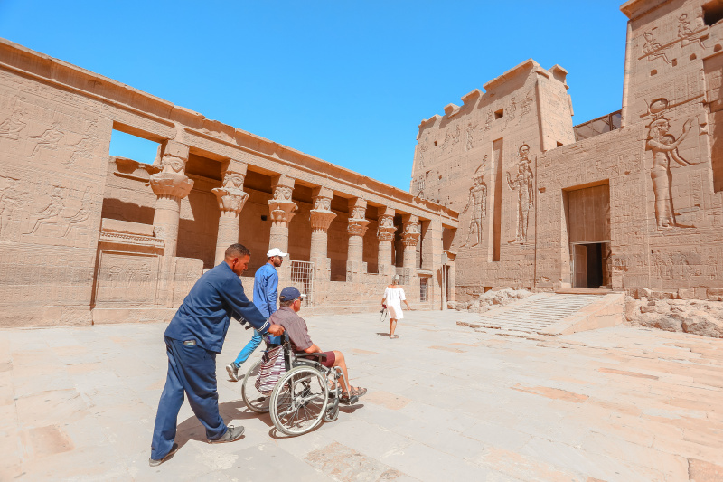 A wheelchair user is helped to explore ancient monuments in Luxor