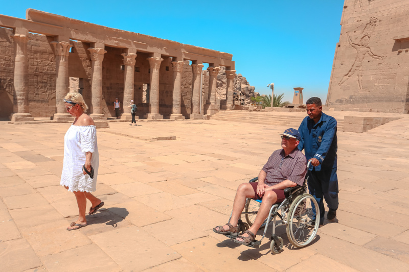 A wheelchair user is helped to explore different Egyptian monuments