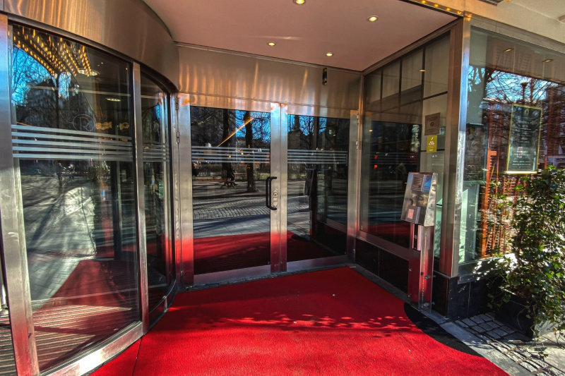 Wide french door entrance to Hotel Rival and red carpet flooring