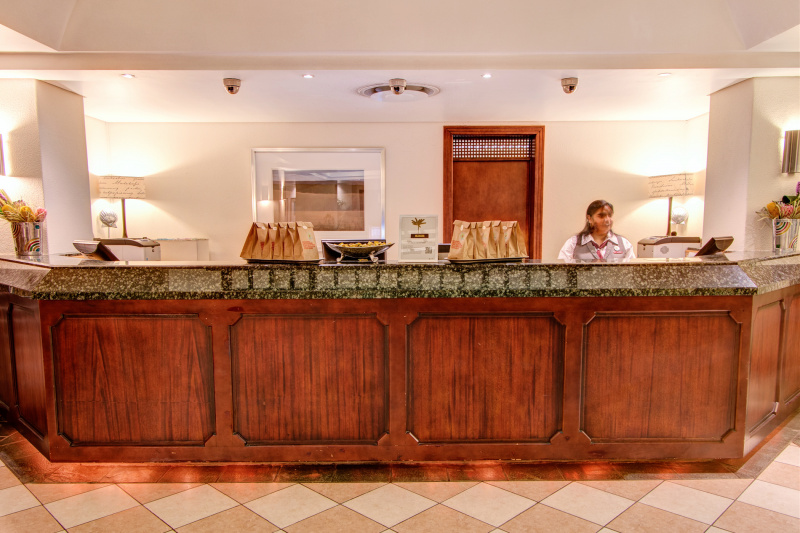 Attendant stands and welcomes guest from behind a raised front desk