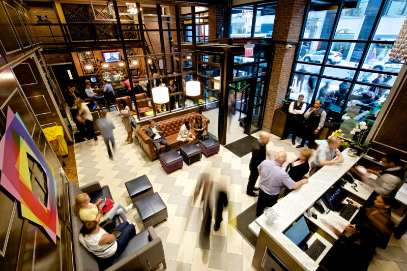 A busy lobby with guests happily moving between the bar and lounge area