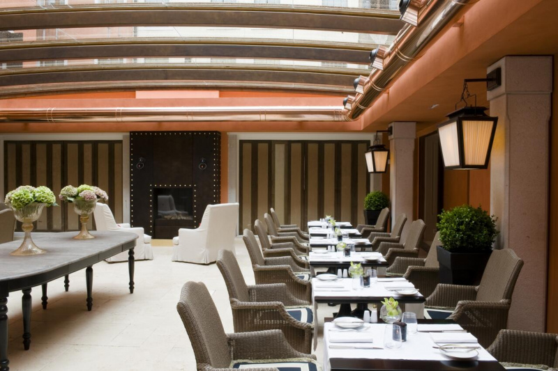 Elegant breakfast area has two seater tables, smooth flooring, and sleek interior design