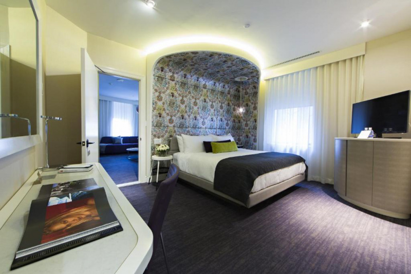 Bedroom fitted with a flat-screen TV and a desk, with wide space around the furniture