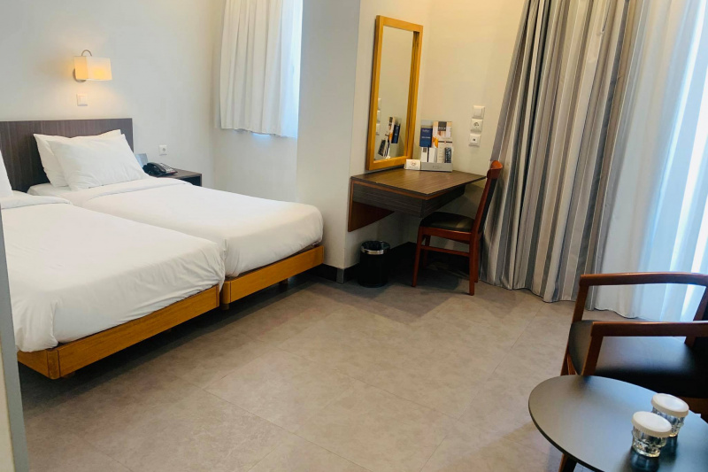 Bedroom with twin beds, seating area, desk and mirror.