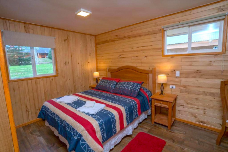 Guestroom with wooden paneling and bed