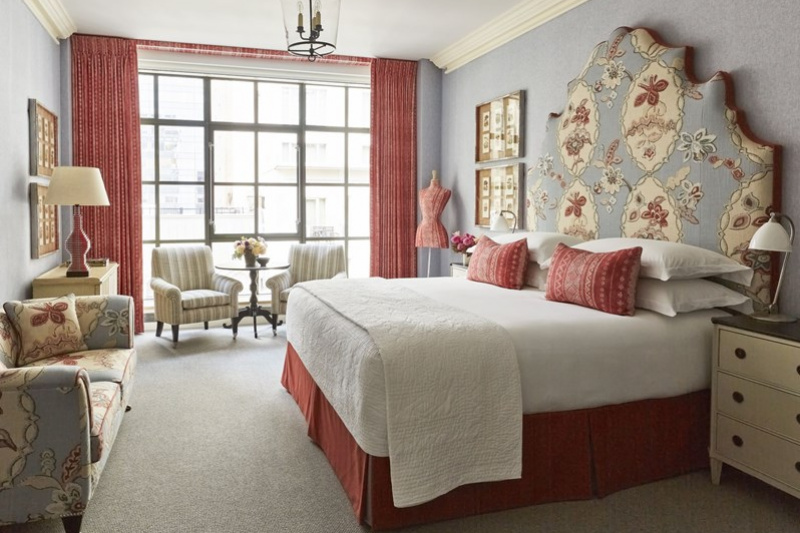 Guestroom with full-length windows, seating area and bed