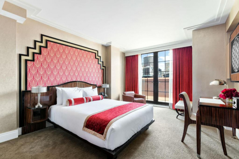 Spacious room with wide space around the bed, seating area by the window, and access to a balcony