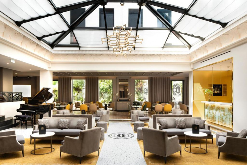 Lobby seating area with piano and glass atrium roof