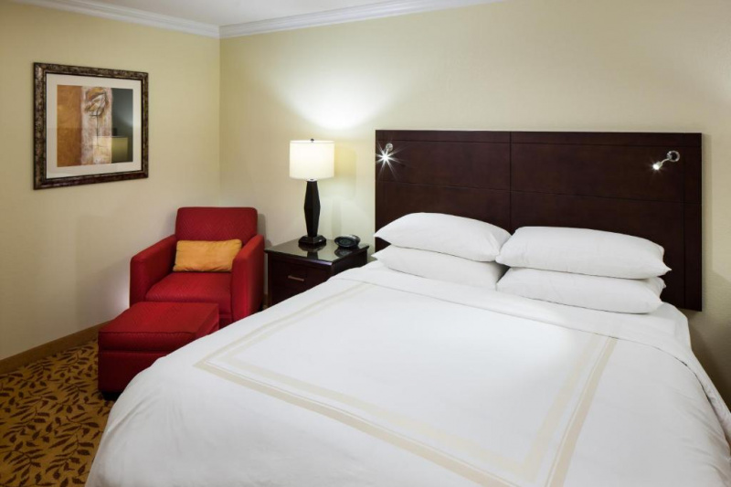 Guestroom bed with nightstands and armchair with footrest