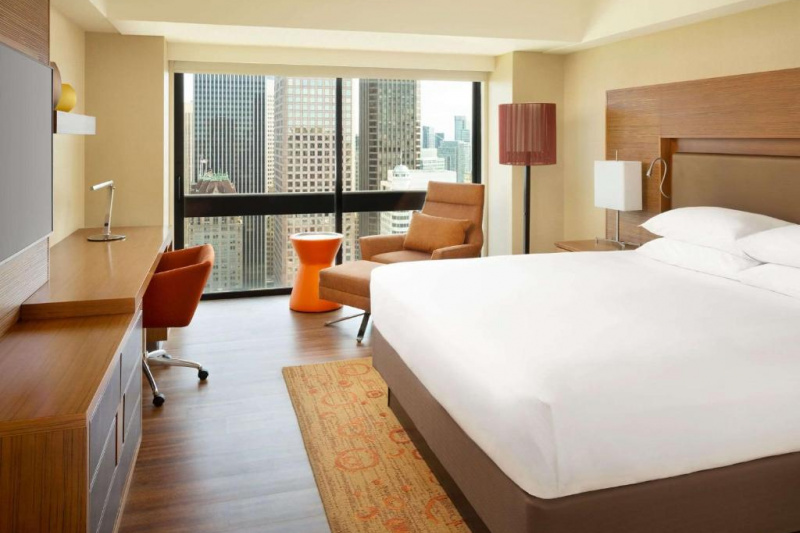 Guestroom with modern decor, wooden flooring and city views