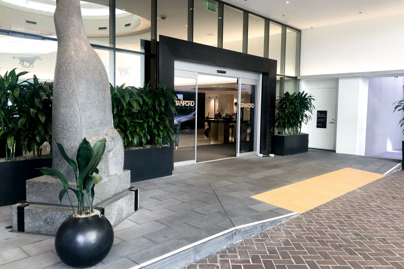 The entrance to the hotel has a wide dropped curb. There are automatic, sliding glass doors that open to give access to the lobby.