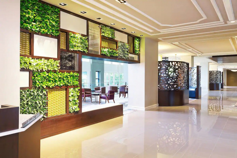 The spacious hotel lobby has marble floors and assorted tables and chairs. There is a wide walkway.