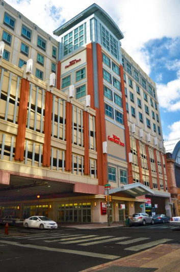This image shows the exterior of the building. It is a modern, 7-story building with large, glass windows. There is a drive-up, covered entrance.