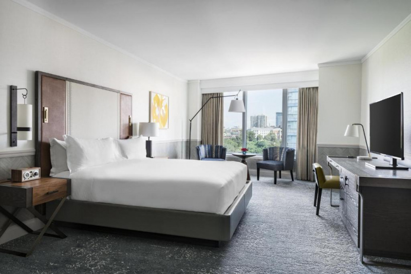 The Deluxe guest room has a king-sized bed with nightstands either side. There is a sofa under the window. Opposite the bed is a cupboard and a TV on top.