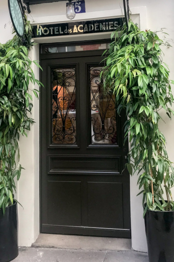 The entrance to the hotel is through a step-free, large single door. There are tall pot plants on either side of it.