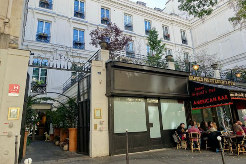 The entrance to the hotel is from the sidewalk. There is a set of tall metal gates that open onto a path leading to the hotel.
