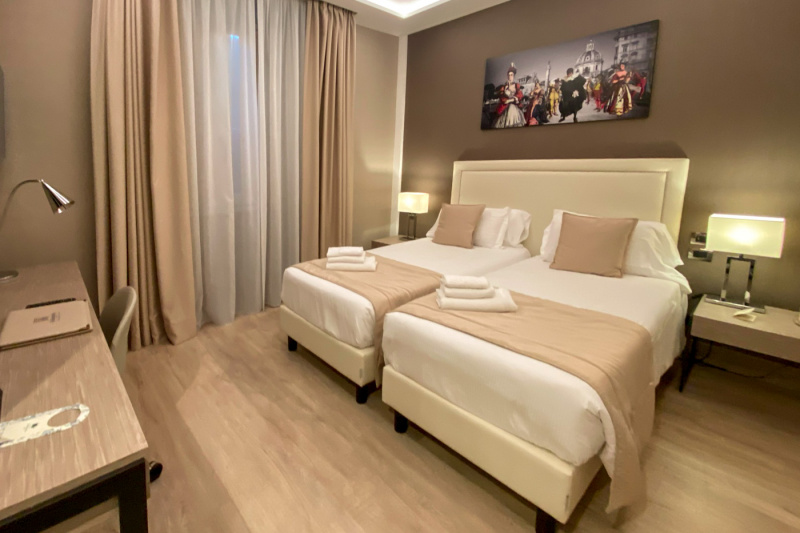 This deluxe double room has two single beds that can be pushed together. There are nightstands and a desk with a chair.