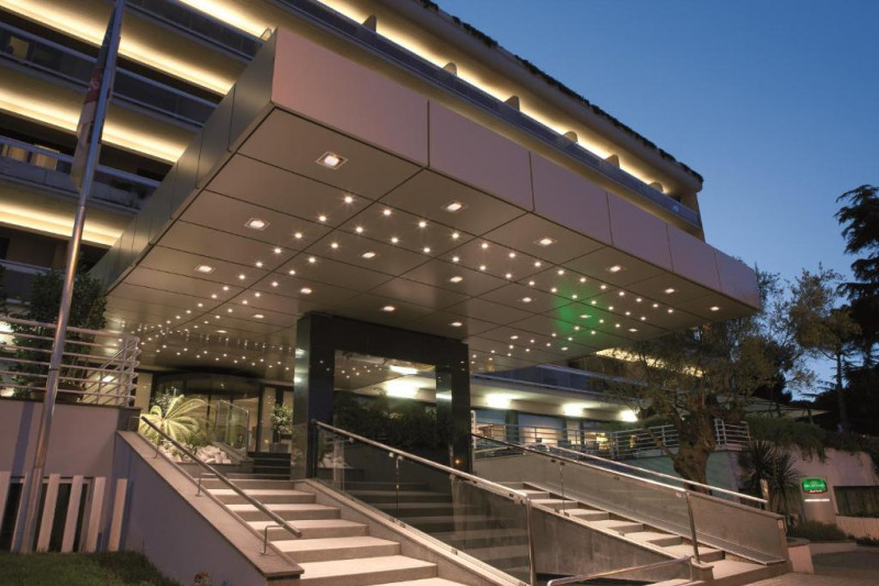 The hotel entrance has two sets of steps leading up to the doors. There are handrails on the sides of the steps.