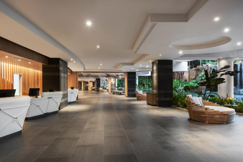 The spacious covered open-sided lobby has several reception desks, one with a dropped counter for wheelchair access. There is comfortable seating overlooking the outdoor waterfall feature.