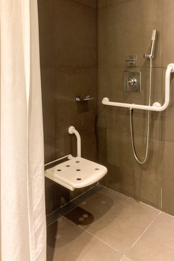 The accessible shower is fitted with grab bars,a shower seat and handheld shower.