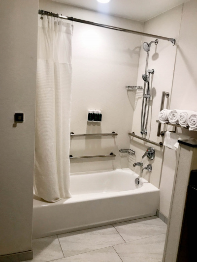 Ensuite restroom with accessible bathtub with grab rails, fixed and handheld shower heads.