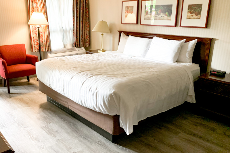 The king bed room has a king-sized bed, nightstands and an armchair and artwork on the wall.