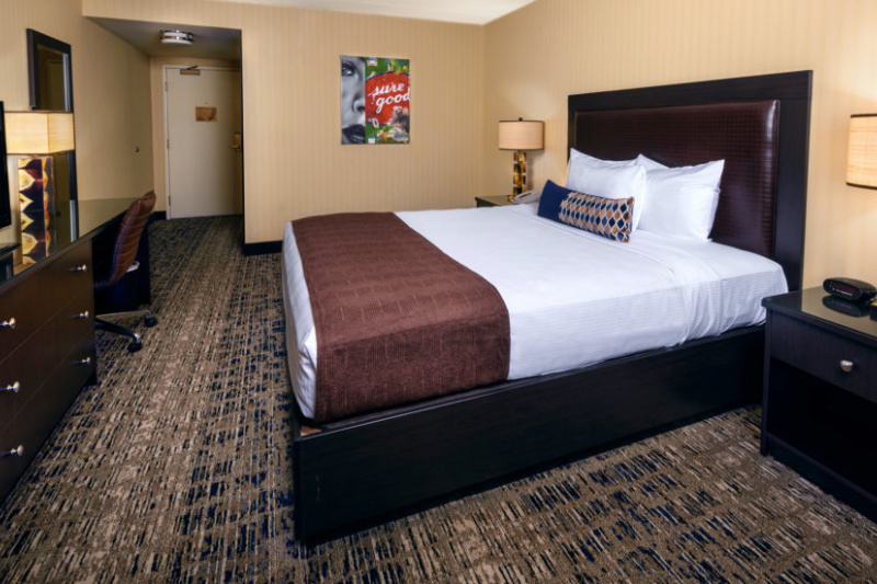 The deluxe king room has a king-sized bed, nightstands, a desk and chair and a cabinet with large TV.