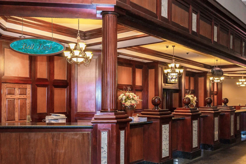 The hotel reception is wood paneled, has chandeliers and a large reception desk.
