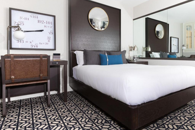 The Urban Cityscape retreat has a queen-sized bed, a nightstand, a desk and chair and a large mirror.