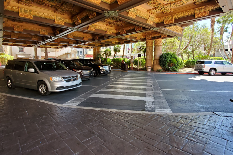 Covered drop-off zone, parking area and taxi rank with ornate ceiling and pedestrian walkway.