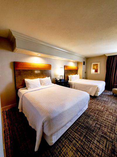 The deluxe room has 2 queen-sized beds, central nightstand with lamp and telephone, wall art and floor-length drapes.