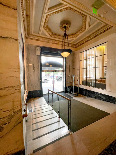 View from lobby to street showing gently sloping railed ramp leading to step-free access to the street through large double glass doors.