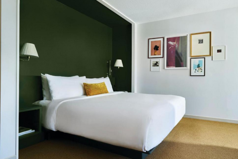 The accessible king has a king-sized bed with white linens, nightstands, wall-mounted reading lamps and artwork on one wall.