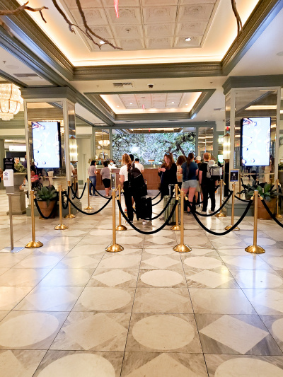 The spacious hotel lobby has a  long regular height check-in desk with a queuing system in places.