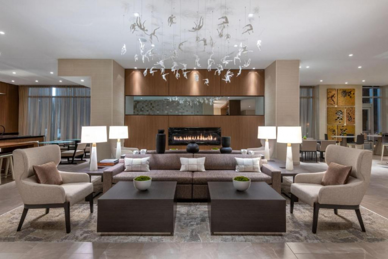 The hotel lobby is spacious and modern with several seating areas featuring comfortable sofas, armchairs, low tables and lamps.