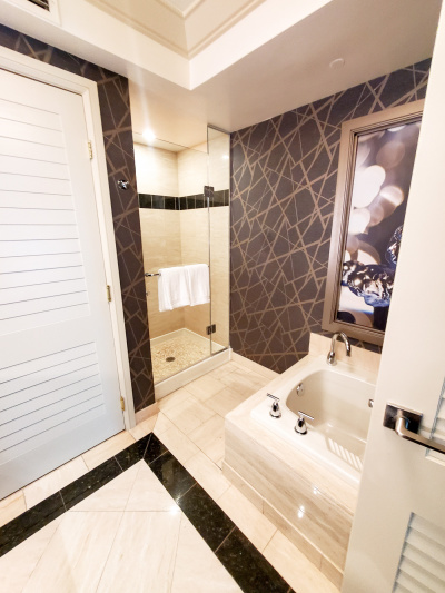 This ensuite restroom has a high bathtub. There is a shower with a step into it.