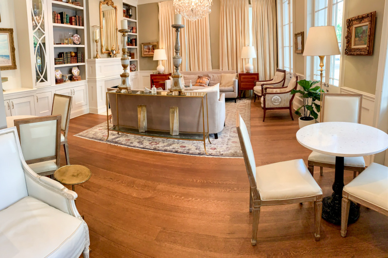 The hotel lobby has comfortable sofas, refined decor with neutral colors a chandelier and a fireplace.There is also a wall unit with books.