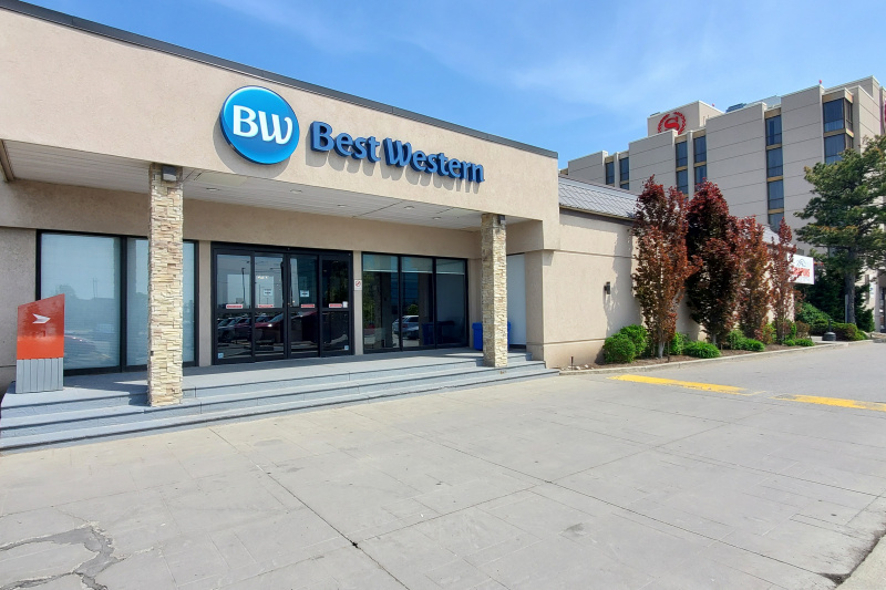 Exterior of the hotel showing three steps up to the automatic glass doors.