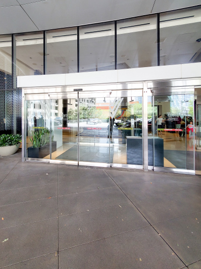 There is step-free access to the hotel entrance through automatic glass doors leading to the hotel lobby, which is flooded with natural light from the all-glass frontage. Inside the entrance there are some plants.