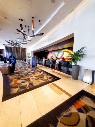 The spacious hotel lobby has marble floors covered with rugs. There is a roped queuing system for the reception desk, which has a high counter, with a lowered wheelchair accessible section at one end.