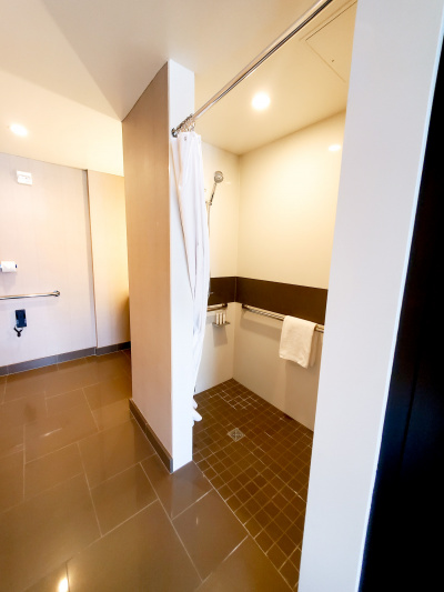 The spacious wide access ensuite restroom has a roll-in shower with grab bars, free toiletries and a shower curtain.