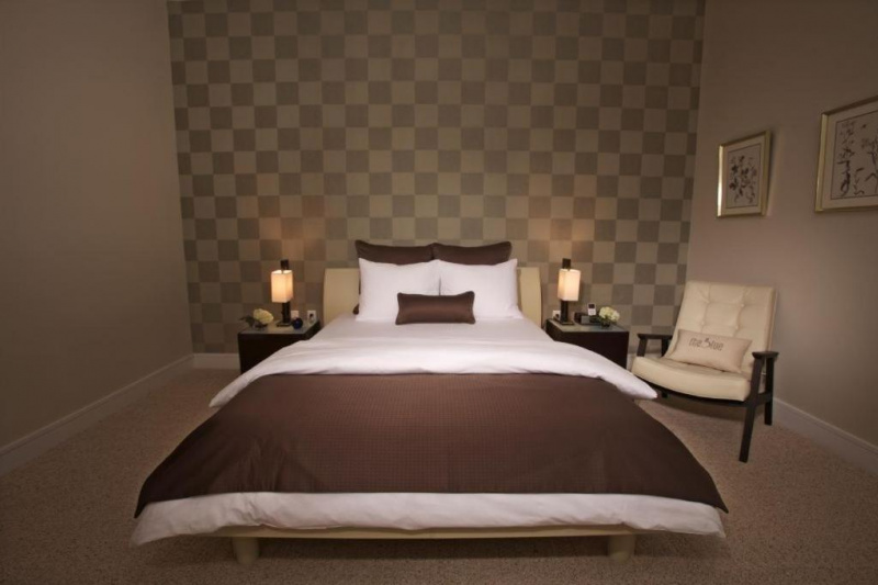 The one bedroom king suite has a king-sized bed, nightstands with lamps and a telephone, an armchair and chequerboard wallpaper behind the headboard.