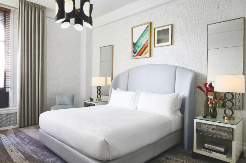 The deluxe king room has a king-sized bed, nightstands and large mirrors and artwork on the walls.
