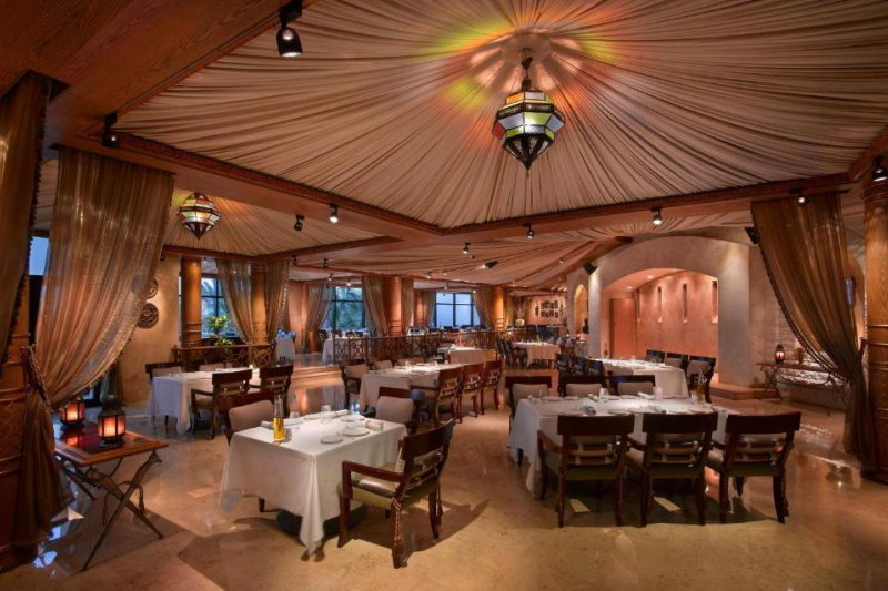 The accessible restaurant has well-spaced assorted tables with white linen and high-back moveable armchairs.